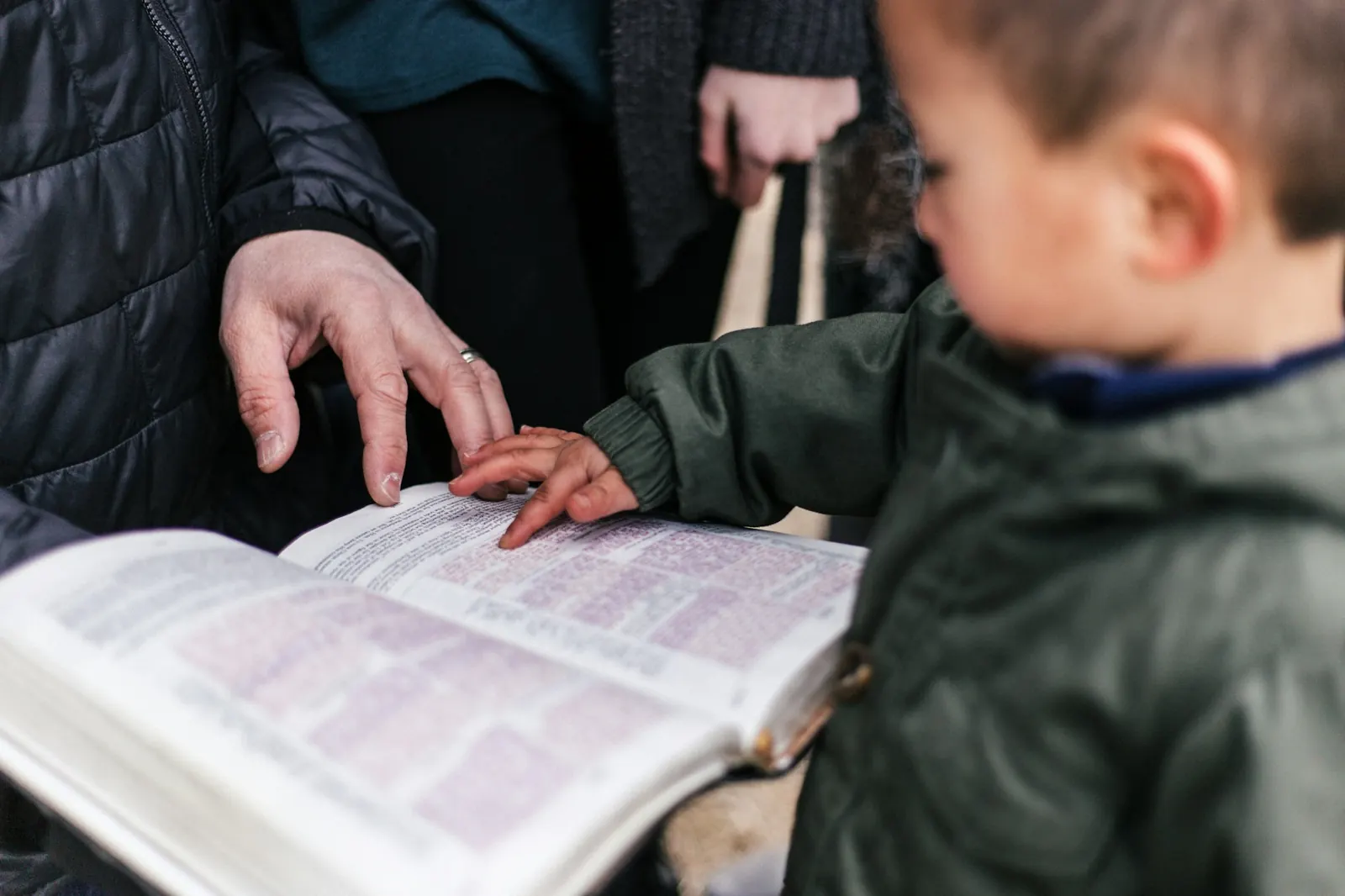 A child and parent reading an open Bible together