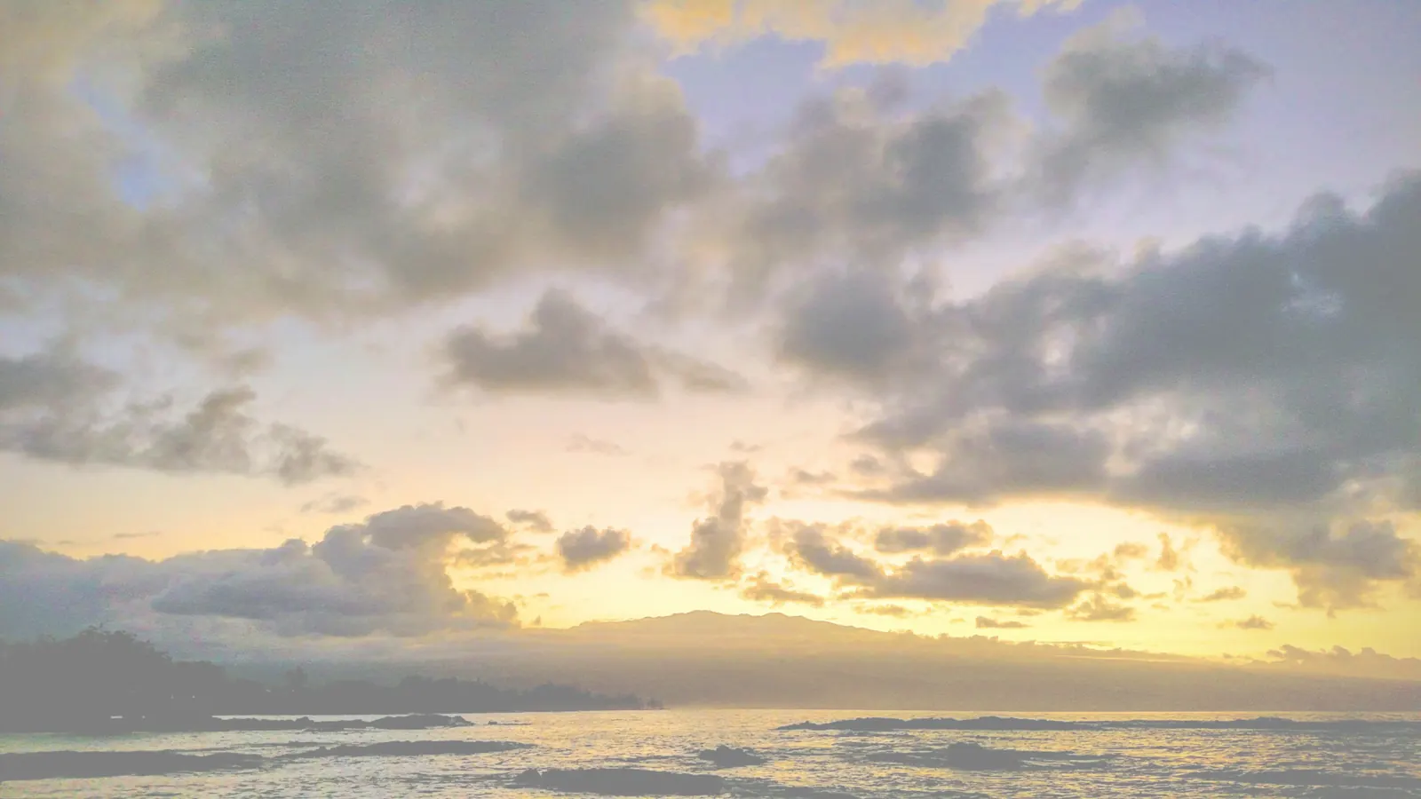 Sunrise over the ocean through scattered clouds